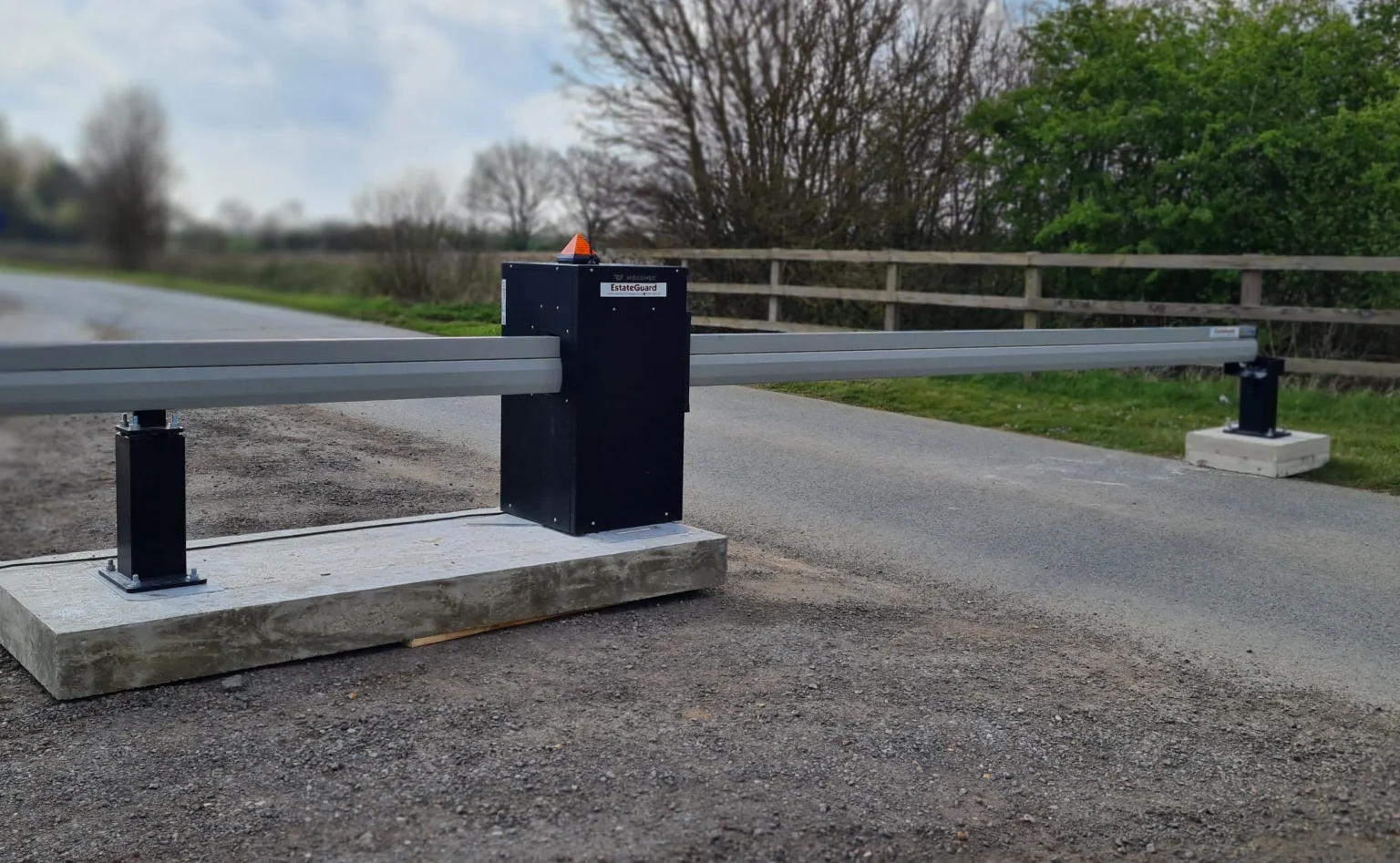 Automatic boom barrier gate system with safety beacon controlling vehicle access on a private road.