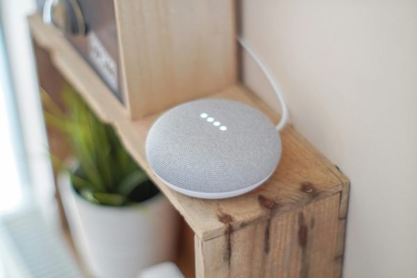 pexels-photo-1072851-1072851 A Google Home Mini smart speaker on a wooden shelf, blending technology with home decor.