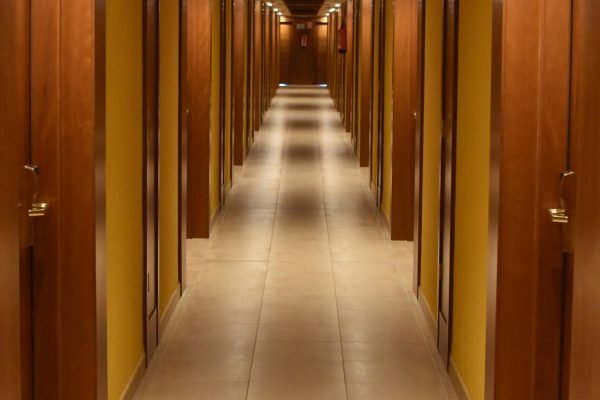 Long hallway view of a modern hotel with wooden doors and ceiling, creating a luxurious ambiance.