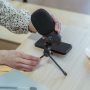 pexels-photo-6953876-6953876 From above of crop unrecognizable female employee setting up microphone while sitting at wooden table with notebook and smartphone during briefing