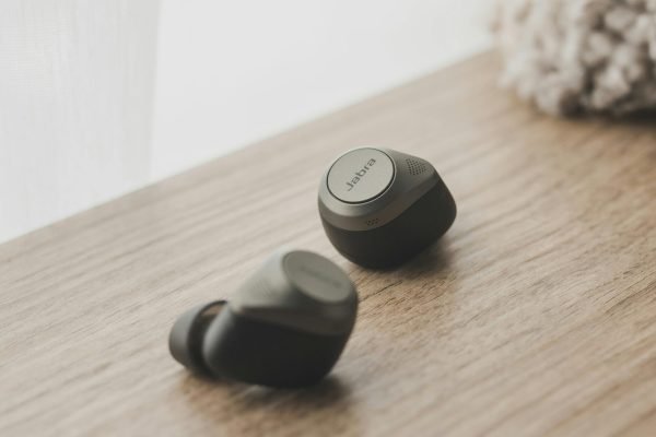 pexels-photo-8360626-8360626 Close-up of sleek wireless earbuds resting on a stylish wooden surface by a window.